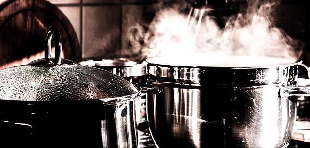 Zwei Kochtöpfe. Aus dem einem steigt dampf aus. Das Bild ist in schwarz weiß und einem leichten rot gehalten.